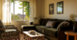 A cozy sitting space with a velvet sofa, rustic wooden coffee table, and warm sunlight streaming through a window
